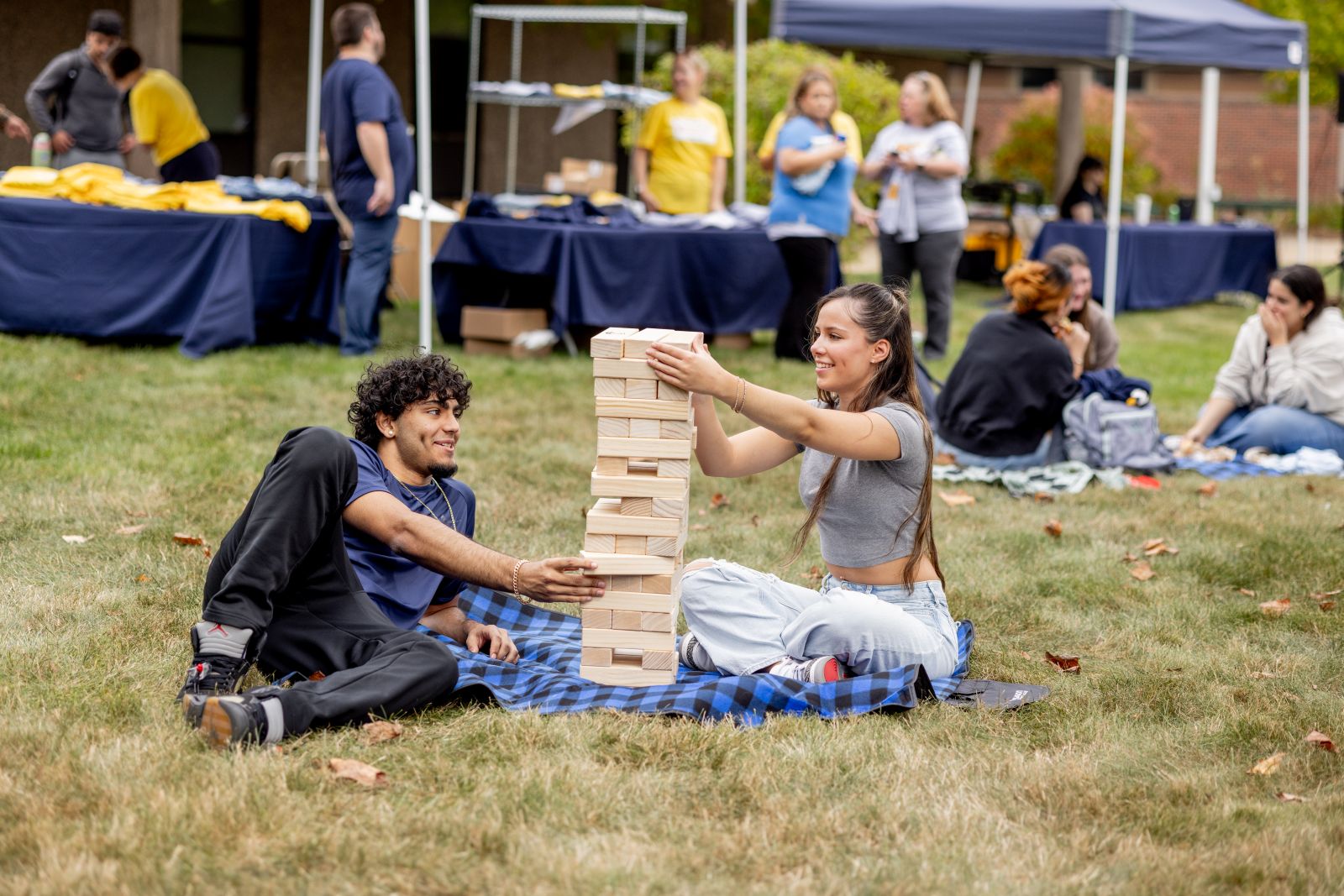Massasoit_BBQ_9-24-296 Students playing Jenga on a picnic blanket.